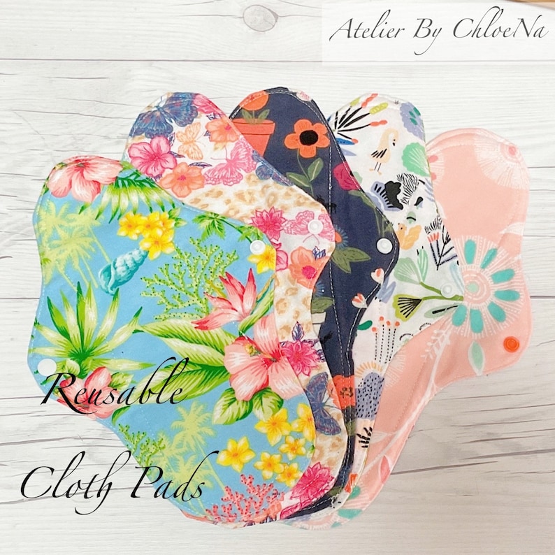 May include: A stack of five reusable cloth pads with floral patterns. The pads are in various colors, including blue, pink, white, and black. The text "Reusable Cloth Pads" is written on the bottom of the image.