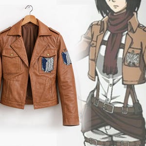 Op de afbeelding: Een bruinleren jas met een kraag, twee borstzakken met knoopsluiting en geborduurde blauw-witte vleugelemblemen op de borst en mouwen, geïnspireerd op het uniform van het Survey Corps uit Attack on Titan.