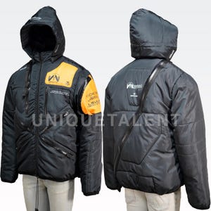May include: Black hooded jacket with orange panels and multiple zipped pockets. The jacket has text and logos on the chest and sleeve. The jacket is displayed on a mannequin. The word "UNIQUETALENT" is printed on the bottom of the jacket.