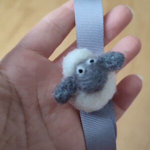 May include: A gray and white felt sheep keychain attached to a gray ribbon.