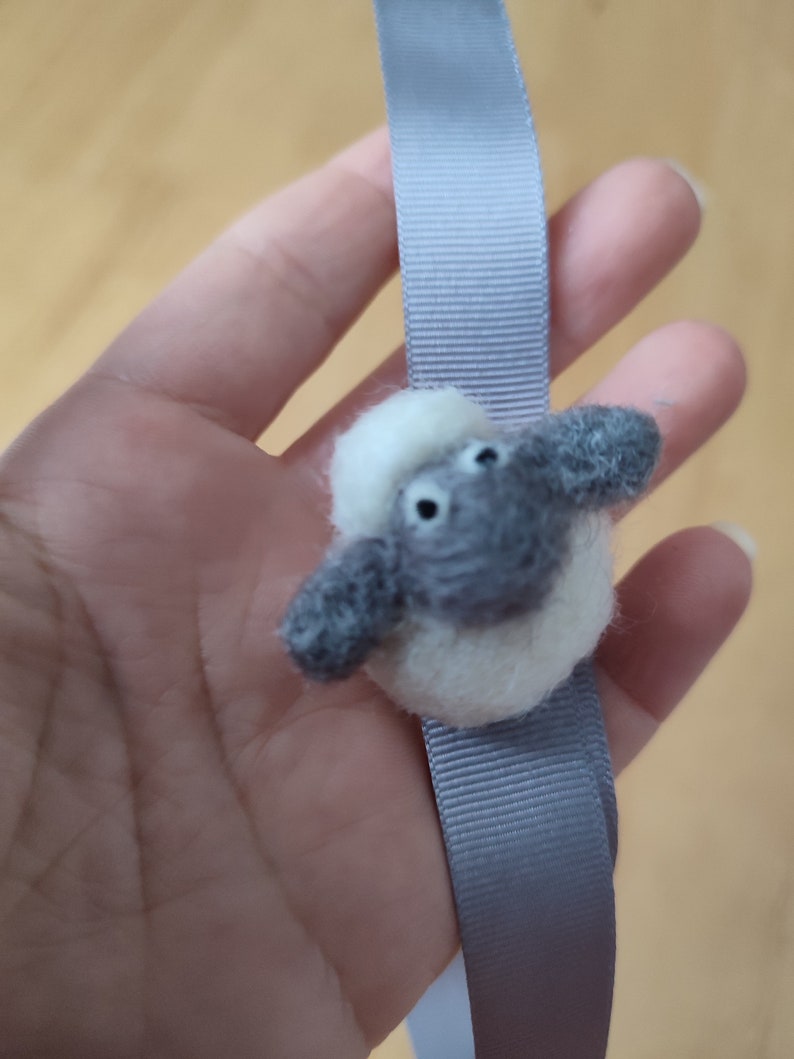 May include: A gray and white felt sheep keychain attached to a gray ribbon.