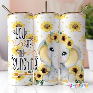 May include: Three white tumblers with a sunflower and elephant design. The tumblers have a yellow and white polka dot background. The text "You are my sunshine" is on the left tumbler.