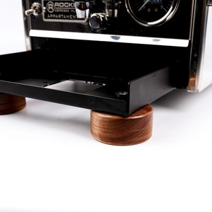 Puede incluir: Máquina de espresso de acero inoxidable con una bandeja negra, apoyada sobre cuatro pies redondos de madera oscura. La máquina tiene un indicador y el texto "ROCKET ESPRESSO MILANO APPARTAMENTO".
