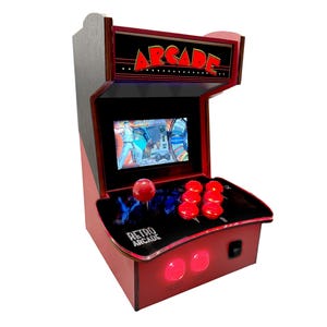 May include: A red and black retro arcade game console with a small screen, joystick, and buttons. The console has the word "ARCADE" printed on the top and "RETRO ARCADE" printed on the front.