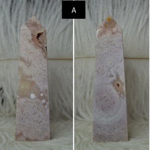 May include: Two pink and white crystal obelisks. The obelisks have a rectangular base and a pointed top. The crystal has a textured appearance with a mix of pink and white hues. One obelisk has a small cavity.