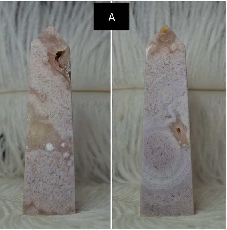 May include: Two pink and white crystal obelisks. The obelisks have a rectangular base and a pointed top. The crystal has a textured appearance with a mix of pink and white hues. One obelisk has a small cavity.