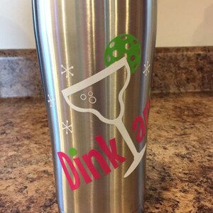 May include: Stainless steel tumbler with a pink "Dink and" text and a white margarita glass with a green lime wedge. The tumbler has a white snowflake design.