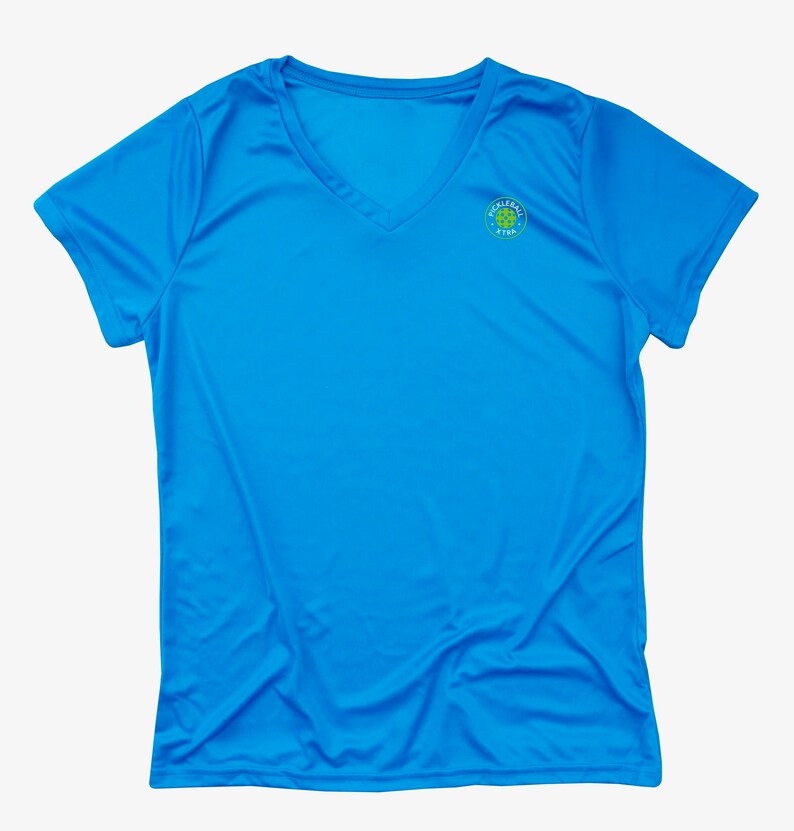 K&ouml;nnte beinhalten: Ein hellblaues T-Shirt mit V-Ausschnitt und einem kleinen gr&uuml;n-gelben Logo auf der rechten Brustseite. Das Logo lautet "Pickleball Star".