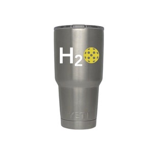 May include: A stainless steel tumbler with a black lid. The tumbler features the text "H2" in white, with a yellow pickleball graphic. The tumbler is designed to keep beverages cold or hot.