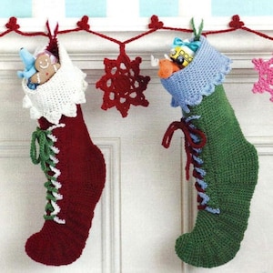 May include: Two crocheted Christmas stockings, one red and one green, with white lace trim and green and white laces. The stockings are hanging from a white mantel with a garland of red hearts and snowflakes.