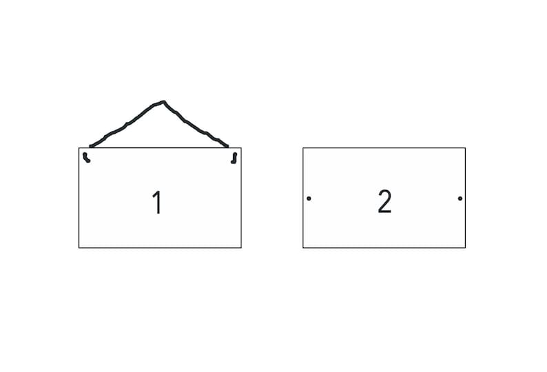 May include: Two white signs with black borders. The sign on the left has a black string hanging from it and the number "1" written on it. The sign on the right has the number "2" written on it.