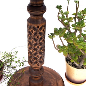 Close-up view of dark wood turned plant stands highlighting the intricate geometric carvings on the central columns. Solid wood classic jardinières with round tops and bases, perfect for displaying trailing plants.