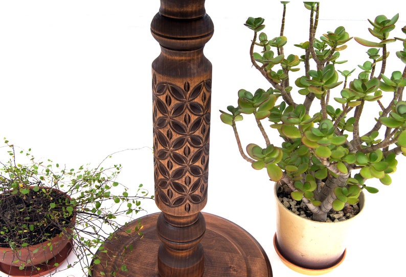 Close-up view of dark wood turned plant stands highlighting the intricate geometric carvings on the central columns. Solid wood classic jardinières with round tops and bases, perfect for displaying trailing plants.