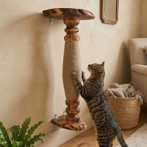 Peut inclure: Un griffoir mural pour chat en bois, avec un dessus et une base à bords naturels. La colonne centrale est recouverte de corde. Un chat tigré est montré en train de l'utiliser.