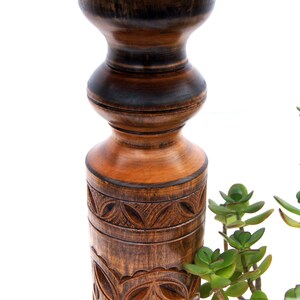 Close-up view of dark wood turned plant stands highlighting the intricate geometric carvings on the central columns. Solid wood classic jardinières with round tops and bases, perfect for displaying trailing plants.