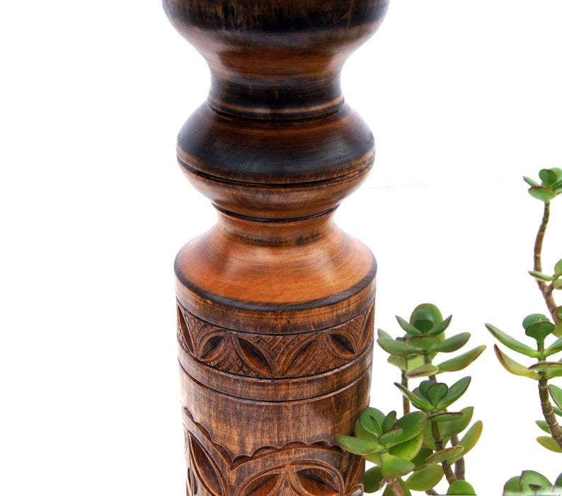 Close-up view of dark wood turned plant stands highlighting the intricate geometric carvings on the central columns. Solid wood classic jardinières with round tops and bases, perfect for displaying trailing plants.