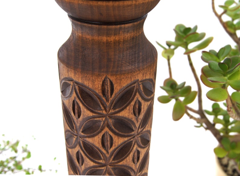 Close-up detail of deep hand-carved geometric motifs on a dark wooden plant column. Solid hardwood texture with a silky oil wax finish, showing the craftsmanship of the turned pillar design.