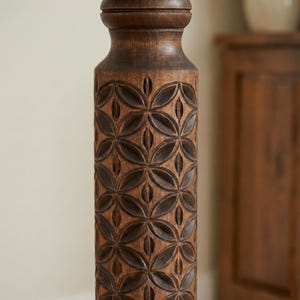 Close-up detail of deep hand-carved geometric motifs on a dark wooden plant column. Solid hardwood texture with a silky oil wax finish, showing the craftsmanship of the turned pillar design.