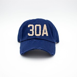 May include: A navy blue distressed baseball cap with a tan embroidered "30A" on the front.