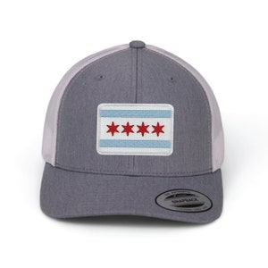 May include: A gray and white trucker hat with a red and white Chicago flag patch on the front. The hat has a mesh back and a snap closure.