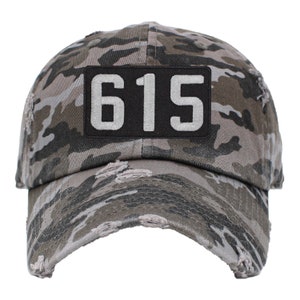 May include: A camouflage baseball cap with a black patch that says "615" in white lettering.