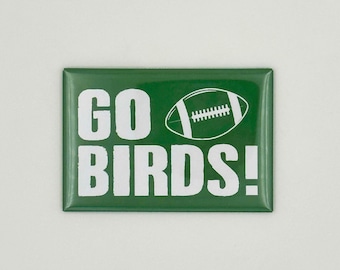 Puede incluir: Imán rectangular verde con texto blanco que dice "GO BIRDS!" y un gráfico de fútbol blanco.