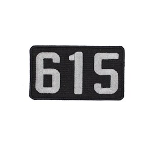 May include: Black rectangular patch with white embroidered numbers "615".