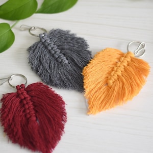 May include: Three handmade macrame feather keychains in gray, orange, and burgundy.