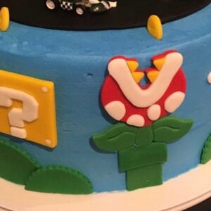 May include: A blue and green cake decorated with a question mark block, a Piranha Plant, and other Super Mario Bros. characters.
