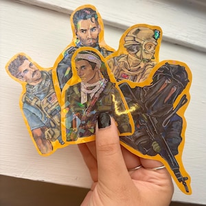 Puede incluir: Un conjunto de cinco pegatinas holográficas con ilustraciones de figuras militares en varios uniformes y equipos. Las pegatinas tienen un contorno amarillo y representan retratos detallados de personajes con armas y equipo táctico.