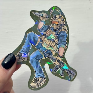 May include: Holographic sticker featuring a soldier in tactical gear, holding a knife and a rifle. The illustration has a green and blue color scheme, with a shiny, iridescent effect. The soldier is wearing a helmet, goggles, and a tactical vest.