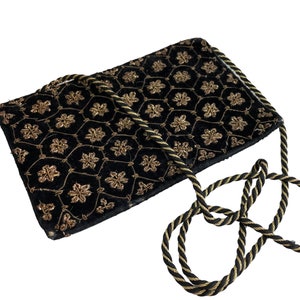 Peut inclure: Un sac de soirée en velours noir avec un motif floral brodé or et une bandoulière en corde noire et or.