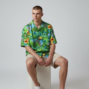 May include: A green button-up shirt with a tropical floral print featuring yellow and orange flowers, palm trees, and a beach scene. Paired with khaki shorts and white sneakers. The shirt has short sleeves.