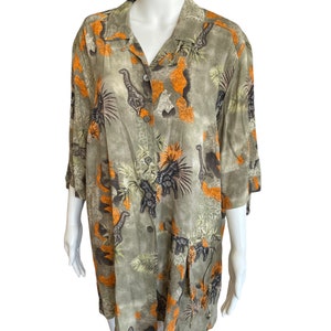 Op de afbeelding: Een groen, oranje en zwart knoopshirt met een safari-dierprint. Het shirt heeft een kraag en korte mouwen.