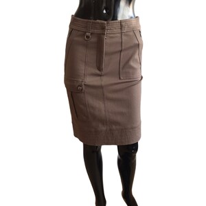 Puede incluir: Una falda marrón, de largo hasta la rodilla, con un bolsillo cargo y un detalle de trabilla para cinturón.