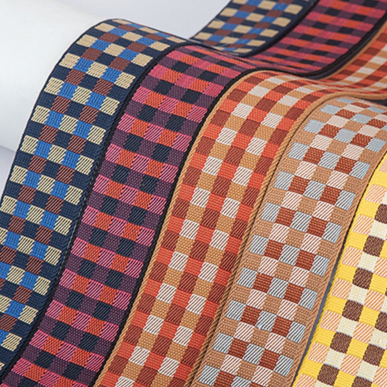 May include: Five different patterned fabric ribbon trims with a checkered design. The ribbons are in shades of brown, red, blue, and yellow.