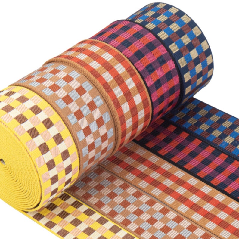 May include: A roll of colorful checkered elastic ribbon. The ribbon is made of woven fabric and has a variety of colors, including yellow, brown, red, blue, and black.