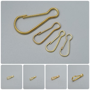 May include: Four gold-colored metal key rings of different sizes. The largest key ring is about 2 inches long, and the smallest is about 1 inch long.