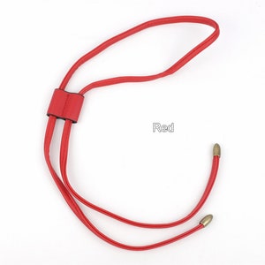 May include: Red leather cord with two gold-toned metal tips. The cord is looped and tied together with a red leather knot.