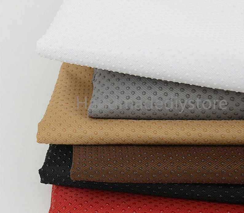 May include: A stack of five fabric swatches in different colors and textures. The swatches are all textured with small raised dots. The colors are white, gray, beige, brown, and red.