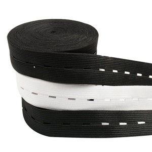 May include: Two spools of black and white elastic with buttonholes sewn along the length. The elastic is rolled up and the white spool is on top of the black spool.