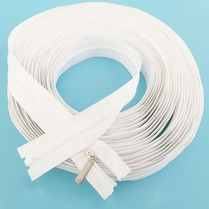 Puede incluir: Una cinta de cremallera blanca, enrollada y lista para proyectos de costura. La cinta de cremallera mide aproximadamente 25 cm de largo y tiene un tirador de cremallera plateado.