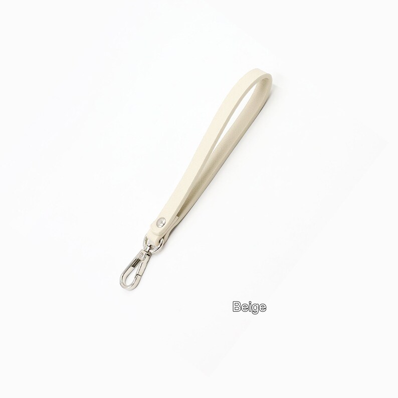 May include: A beige leather strap with a silver swivel clasp. The strap is about 12 inches long.