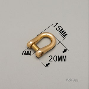 May include: A gold-colored mini-size shackle with dimensions of 20mm x 15mm x 6mm. The shackle has a U-shape with a pin closure. The text "Mini Size" is visible.