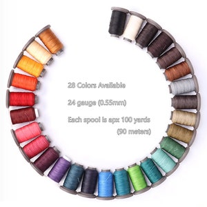 Puede incluir: Disposición circular de 28 carretes de hilo de varios colores. Cada carrete contiene aproximadamente 90 metros de hilo de calibre 24 (0,55 mm). La imagen incluye el texto "28 colores disponibles".