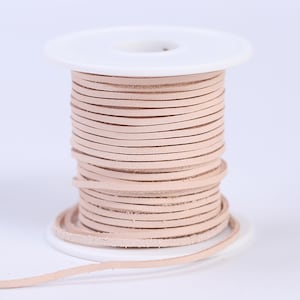 May include: A spool of light pink leather cord, wound around a white plastic spool. The cord is thin and flat, and it is perfect for crafting projects.