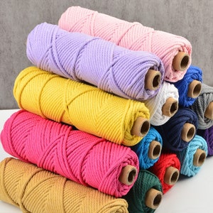 May include: A stack of colorful cotton rope in various colors, including pink, purple, yellow, red, blue, green, and brown. The rope is wound around cardboard tubes.