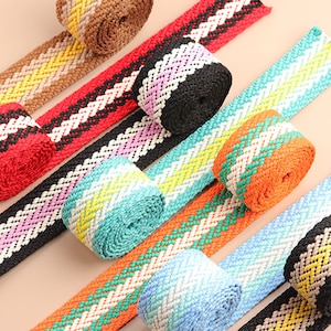 Peut inclure: Assortiment de rubans tissés colorés avec des motifs géométriques. Le ruban est fait d'un matériau texturé et se décline dans une variété de couleurs, notamment le rouge, le bleu, le vert, le jaune, l'orange et le brun.