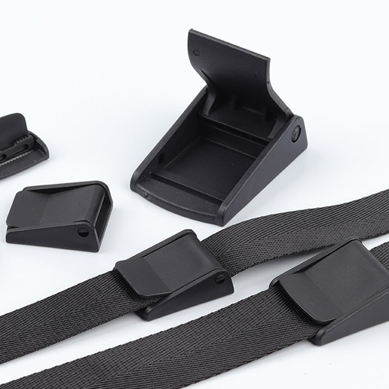 May include: Four black plastic buckles for straps or belts. Two buckles are attached to black webbing straps.