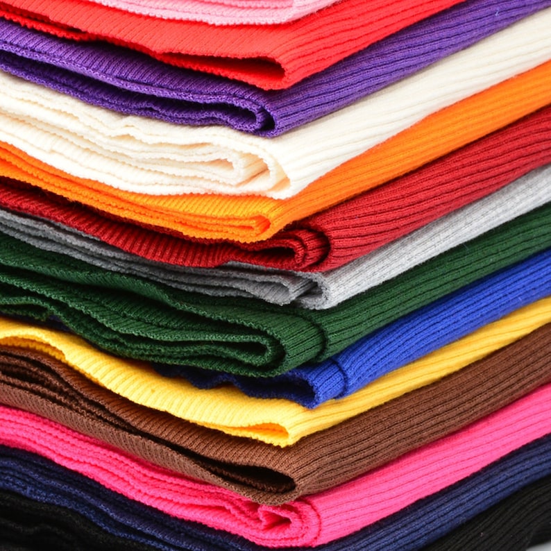 May include: A stack of colorful ribbed fabric in various shades of red, orange, yellow, green, blue, purple, and brown. The fabric is folded neatly and arranged in a layered pattern.
